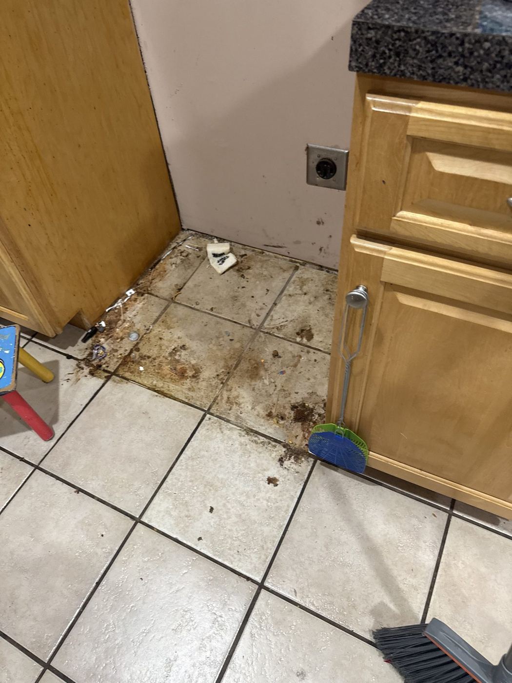 Grease, crumbs and debris on the tile floor behind a kitchen range before a move-out clean