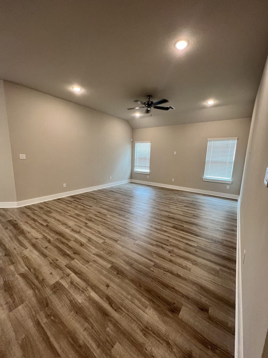 Empty living room with plank floors, ceiling fan and recessed lights after cleaning in Bellaire