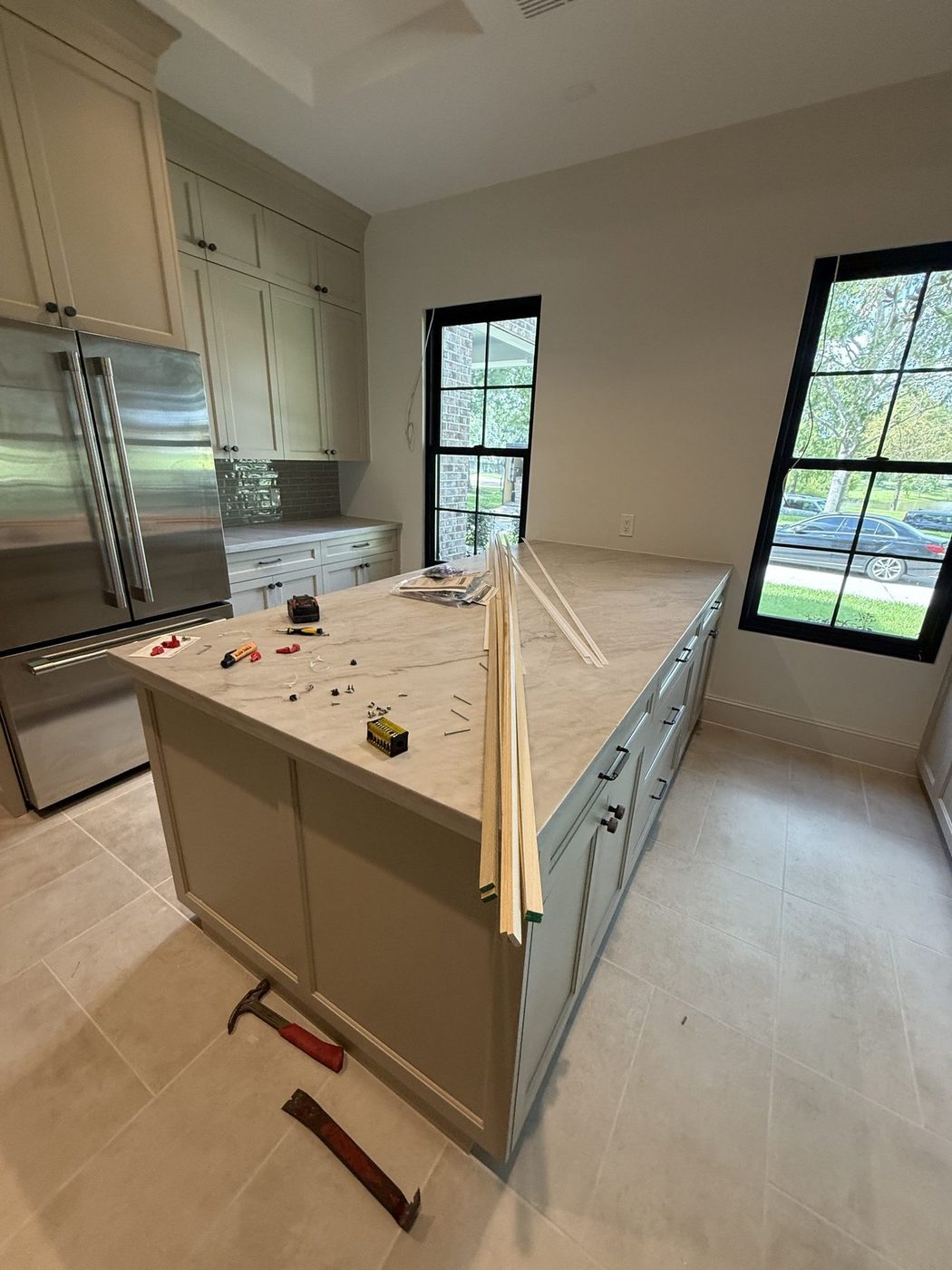 New kitchen island with trim pieces, tools and dust on the countertop before the final clean