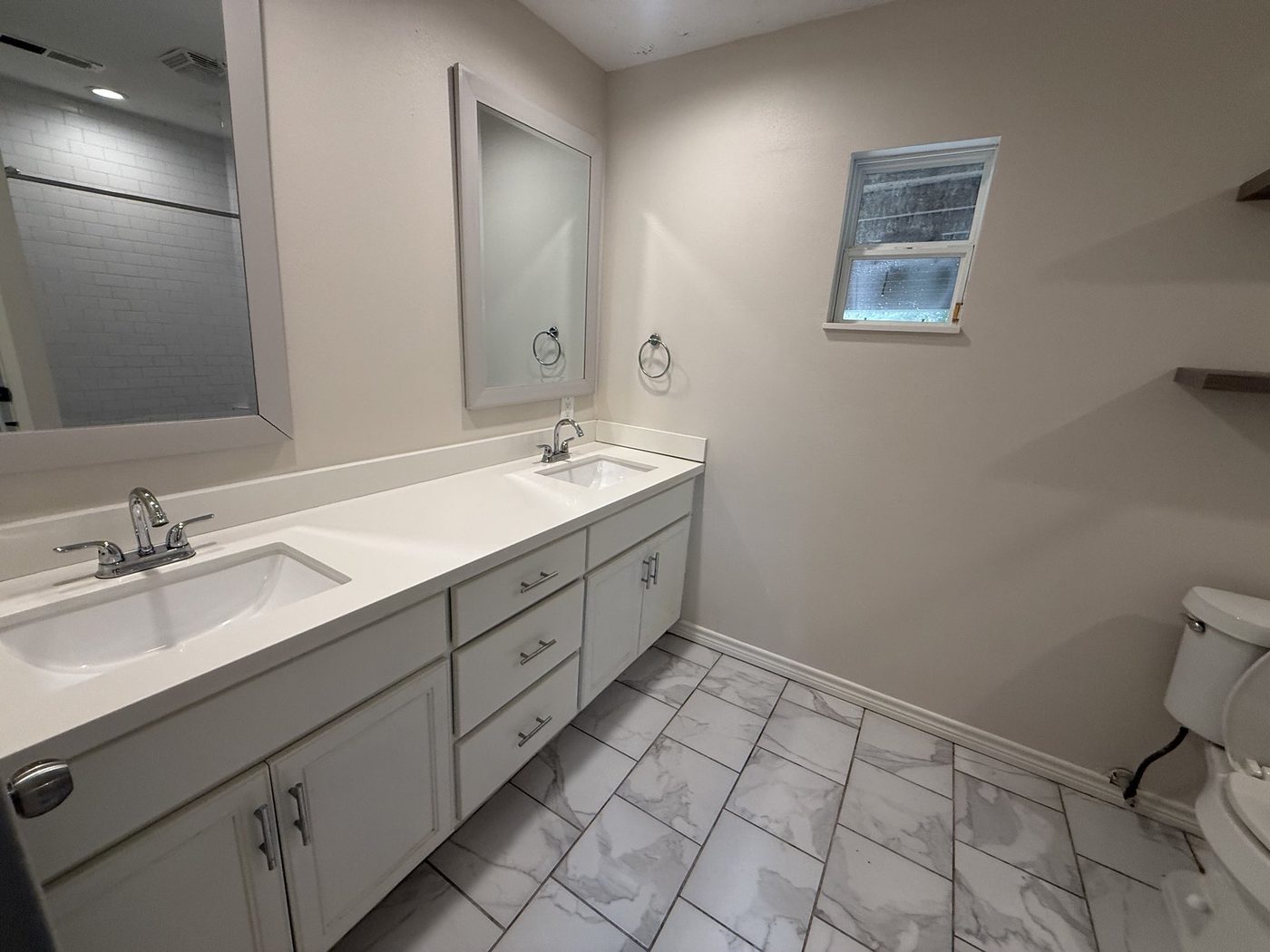 Bathroom with a white double vanity, mirror and tile floor after a Puretek Global Cleaning clean in Houston