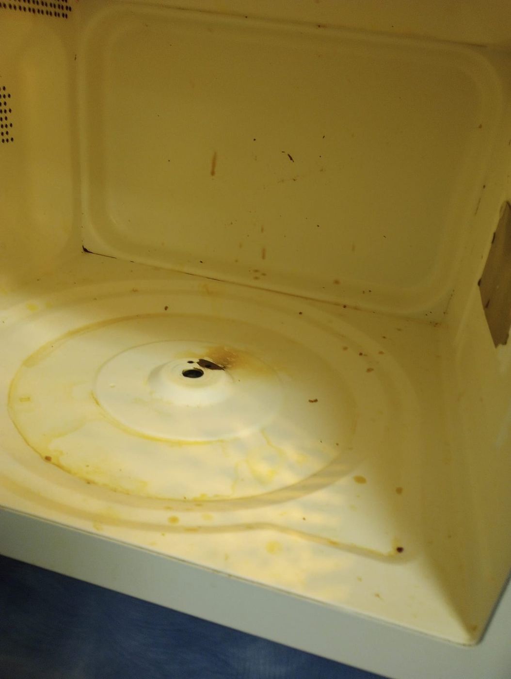 Inside of a microwave with splatter and stains before cleaning