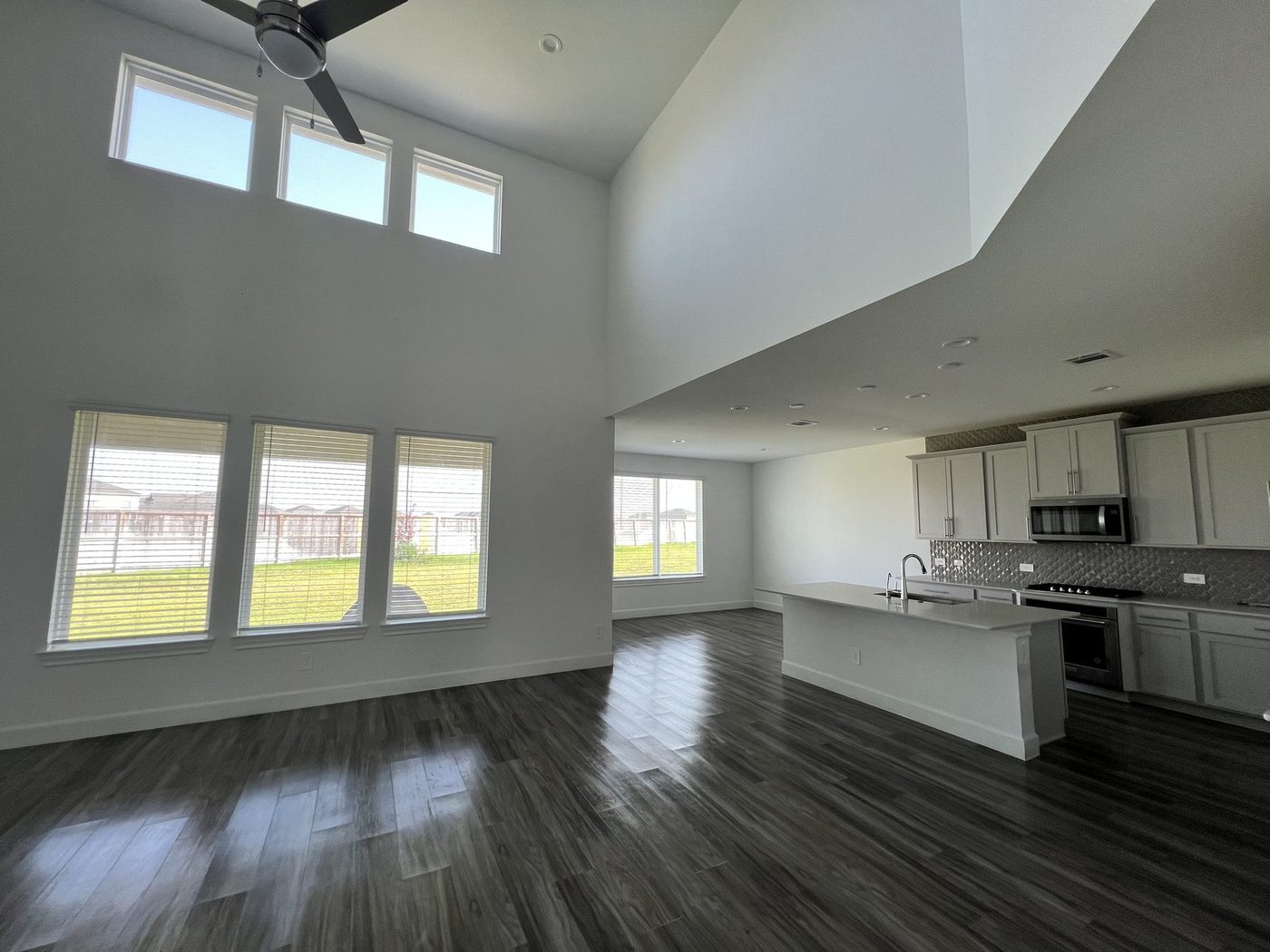 Open great room and kitchen with dark wood-look floors after a Puretek Global Cleaning final clean on a new-construction home in the Houston area