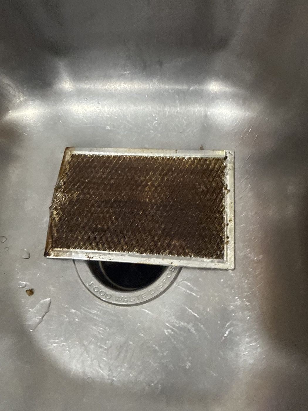Grease-coated metal range hood filter removed from above a stove